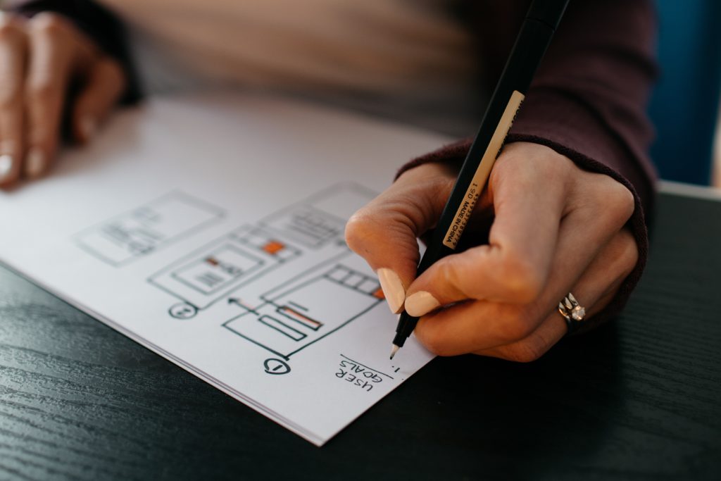 A person wireframing a website with pen and paper.