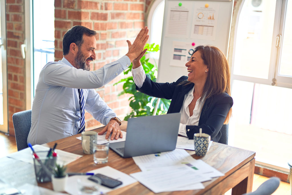 Co-Workers high fiving in a boardroom.